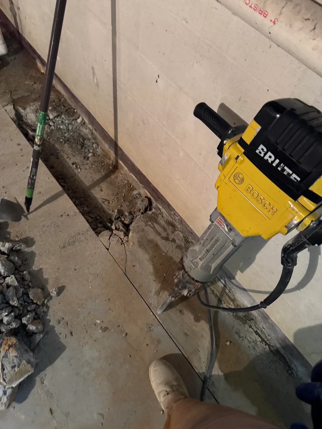 Basement waterproofing Syracuse NY cost, a crew installing a system in a city home